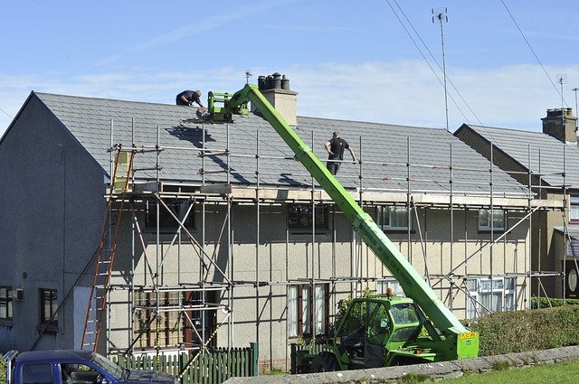 House with scaffold and roofers working on the roof.